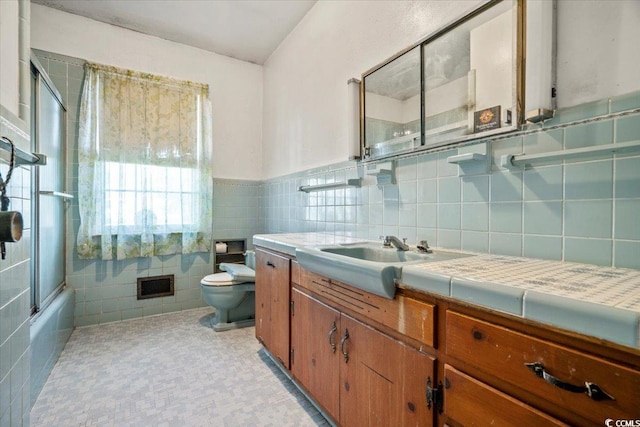 full bathroom featuring vanity, toilet, tile walls, and bath / shower combo with glass door