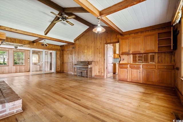 unfurnished living room featuring vaulted ceiling with beams, light wood-type flooring, ceiling fan, and wood walls