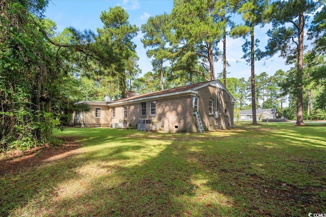 rear view of property featuring a lawn and central AC