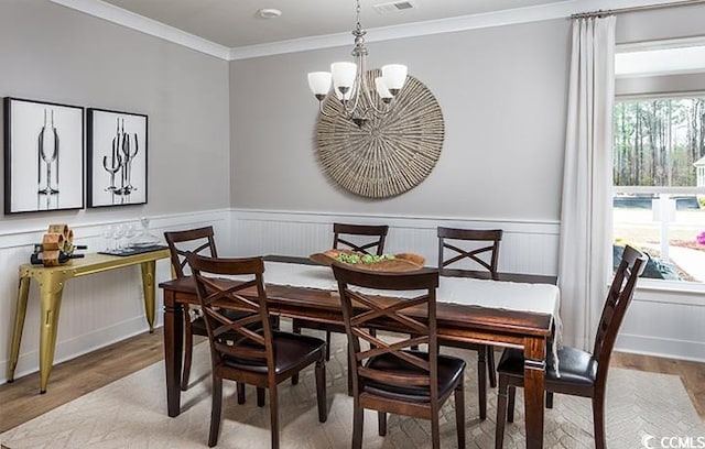 dining space with an inviting chandelier, ornamental molding, and hardwood / wood-style floors