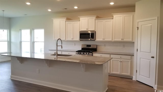 kitchen with stainless steel appliances, a kitchen bar, a kitchen island with sink, and sink