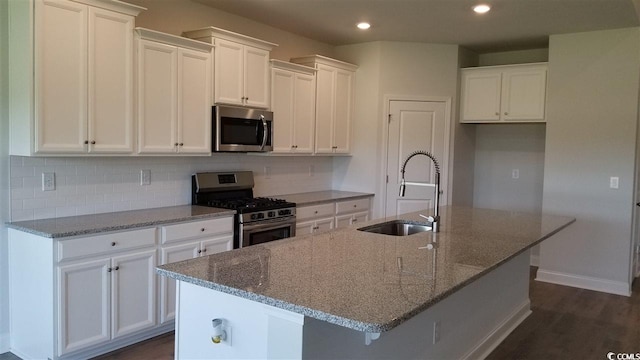 kitchen with an island with sink, stainless steel appliances, dark hardwood / wood-style floors, and white cabinetry