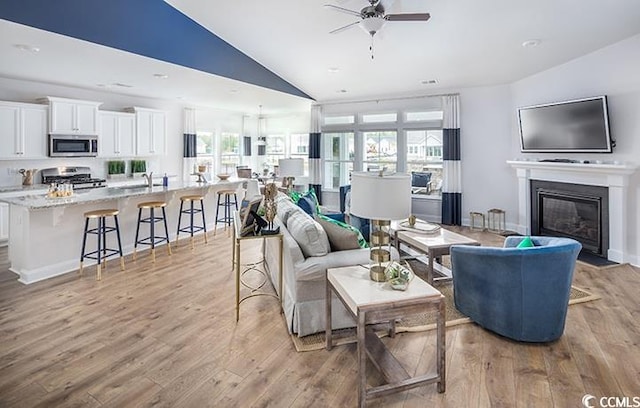 living room with ceiling fan, lofted ceiling, light hardwood / wood-style floors, and a healthy amount of sunlight