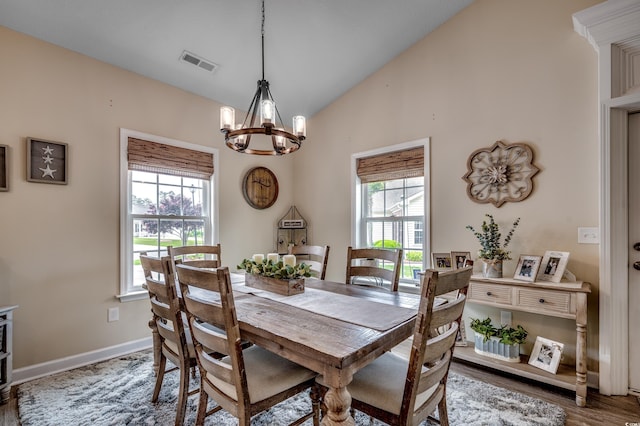 dining area featuring an inviting chandelier, wood-type flooring, high vaulted ceiling, and a healthy amount of sunlight