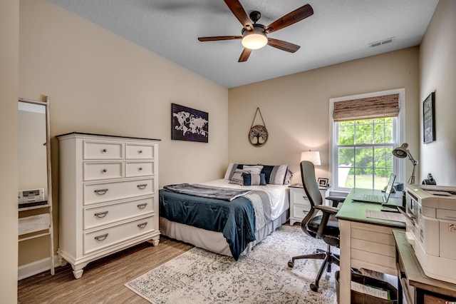 bedroom featuring ceiling fan, a textured ceiling, and light hardwood / wood-style floors