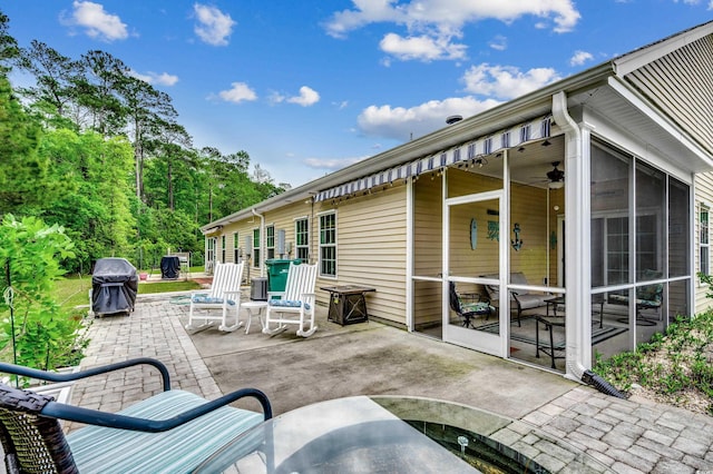 view of patio featuring ceiling fan, a sunroom, and a grill