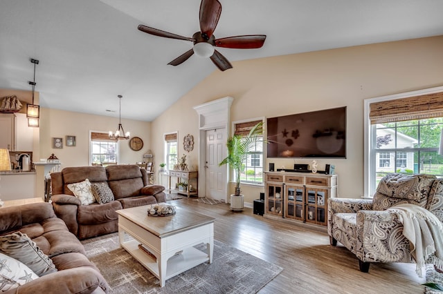 living room featuring ceiling fan with notable chandelier, light wood-type flooring, and vaulted ceiling