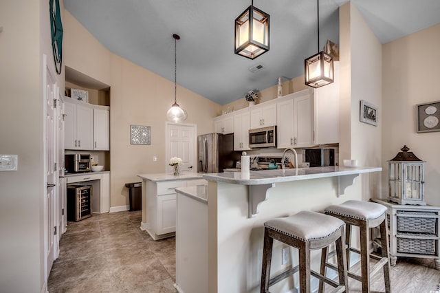 kitchen with decorative light fixtures, stainless steel appliances, high vaulted ceiling, and white cabinetry