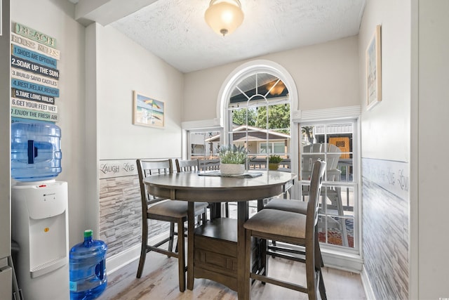 dining space with hardwood / wood-style floors and a textured ceiling