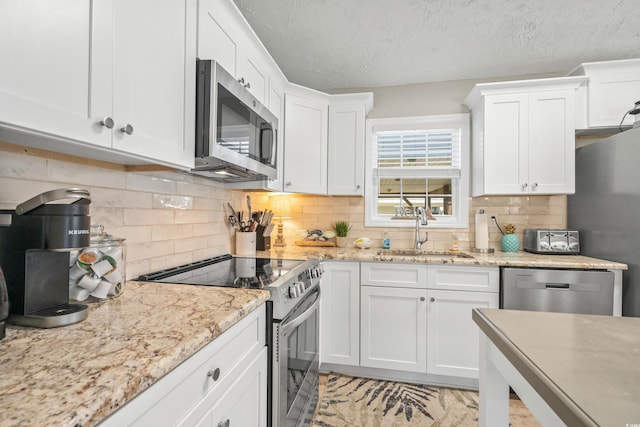 kitchen featuring white cabinets, backsplash, stainless steel appliances, and sink