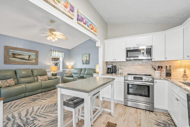 kitchen featuring white cabinets, light wood-type flooring, stainless steel appliances, and vaulted ceiling