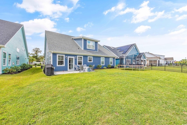 back of property with a lawn, a trampoline, and a patio