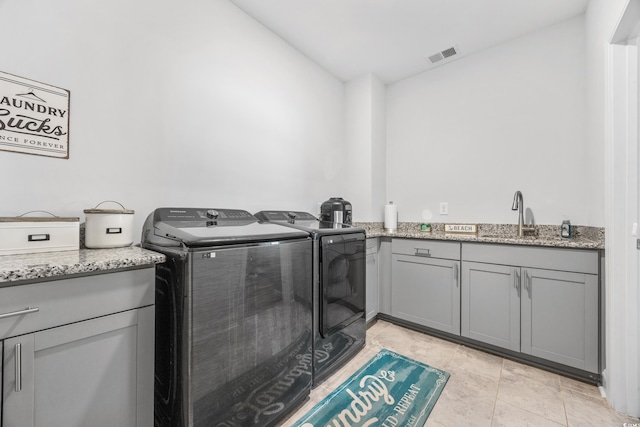 clothes washing area featuring washer and clothes dryer, light tile patterned flooring, cabinets, and sink