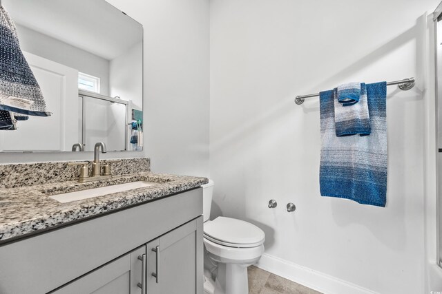 bathroom with an enclosed shower, vanity, toilet, and tile patterned flooring