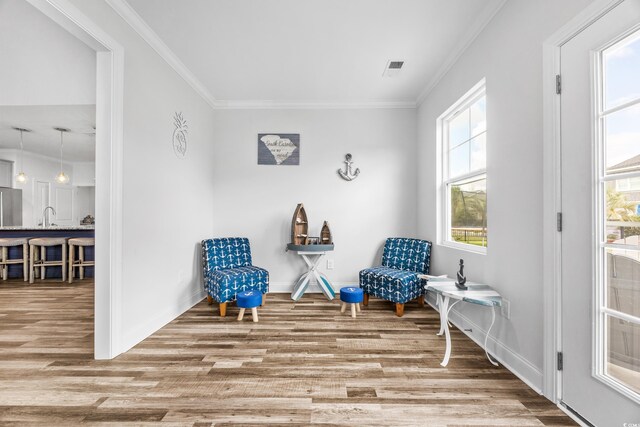 living area featuring hardwood / wood-style floors, crown molding, and sink