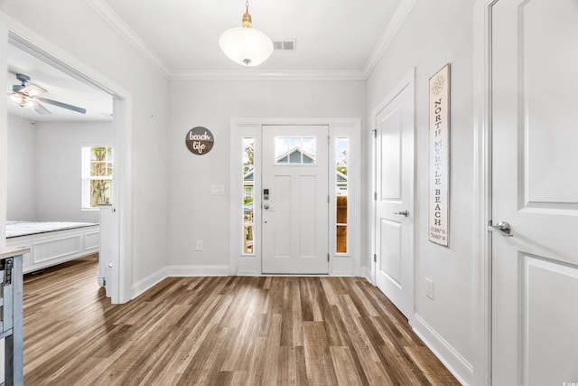 foyer with ceiling fan, dark hardwood / wood-style flooring, and crown molding