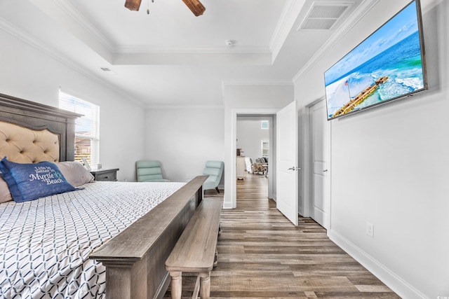 bedroom with hardwood / wood-style flooring, ceiling fan, a raised ceiling, and crown molding