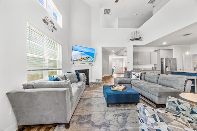 living room featuring light wood-type flooring, a towering ceiling, and ornamental molding