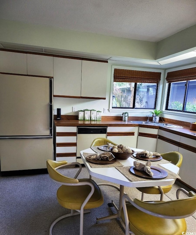 kitchen featuring white cabinetry, stainless steel dishwasher, refrigerator, and a textured ceiling