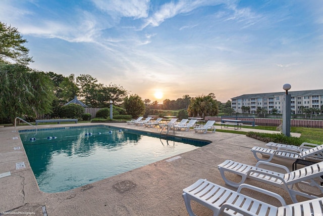 pool at dusk featuring a patio