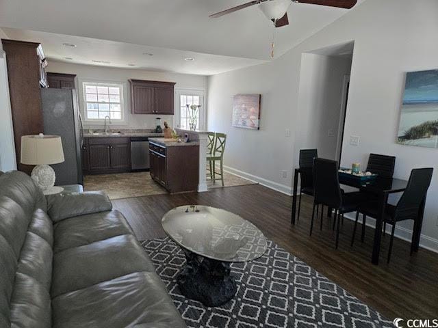 living room featuring dark hardwood / wood-style floors, ceiling fan, sink, and vaulted ceiling