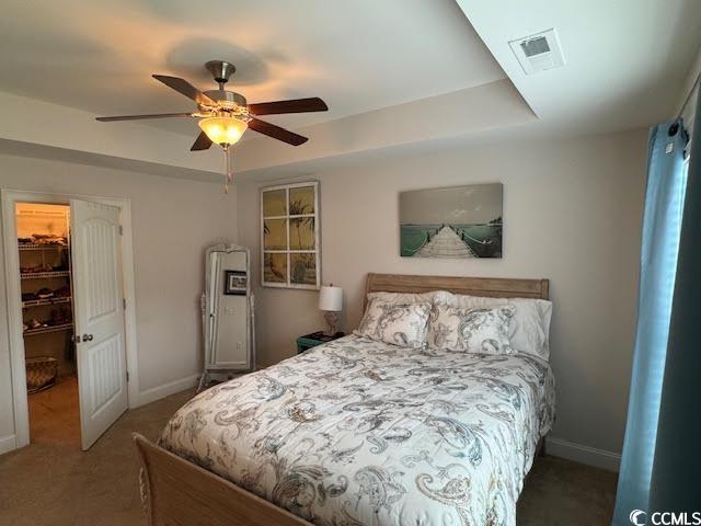 carpeted bedroom featuring a walk in closet, a closet, and ceiling fan