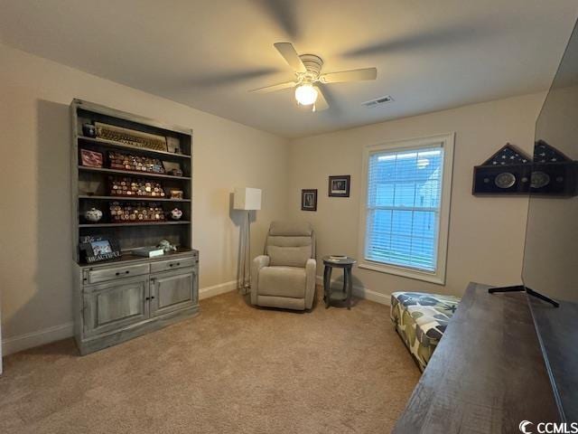 living area featuring light carpet and ceiling fan