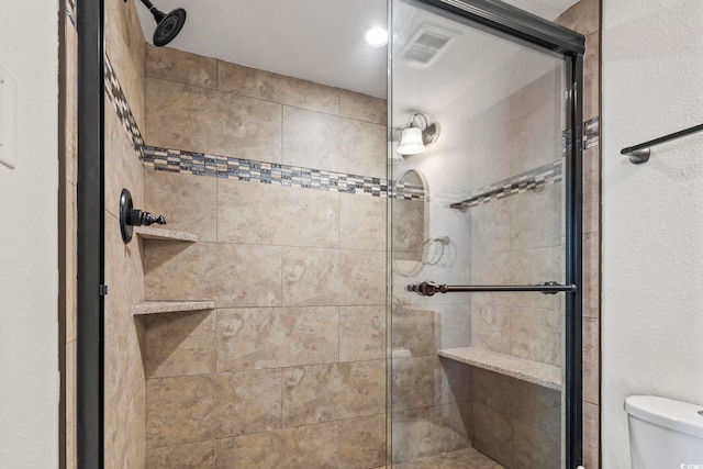 bathroom featuring toilet and a shower with door