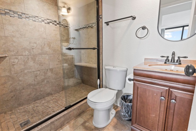 bathroom featuring tile patterned flooring, vanity, toilet, and a shower with door