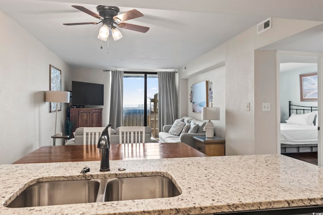 kitchen featuring sink, ceiling fan, and light stone counters