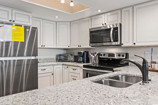 kitchen with white cabinets, sink, stainless steel appliances, and light stone counters