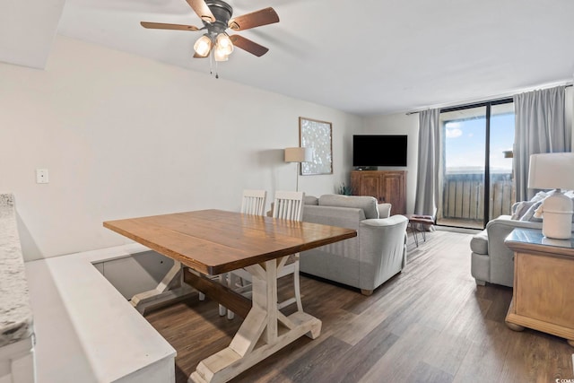 dining room featuring ceiling fan, a wall of windows, and dark wood-type flooring