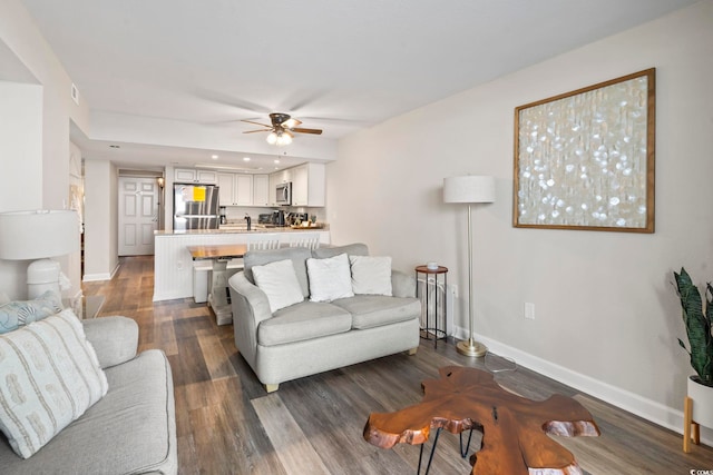 living room with ceiling fan and dark hardwood / wood-style flooring