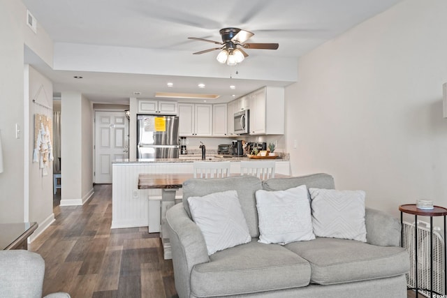 living room featuring ceiling fan and dark wood-type flooring