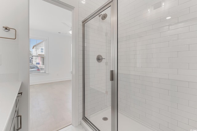 bathroom with a shower with door, ceiling fan, and vanity