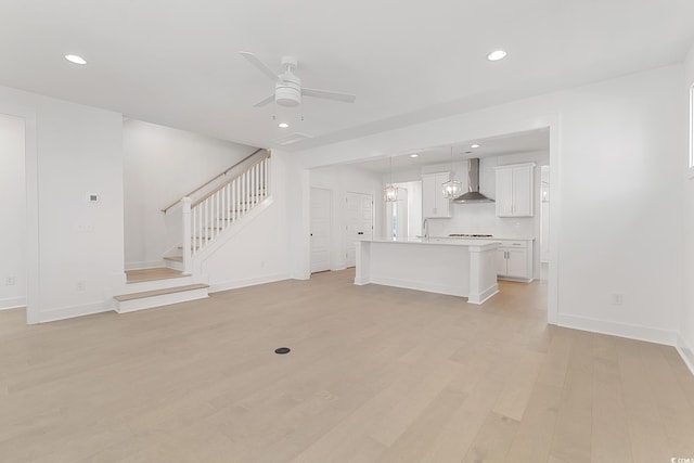 unfurnished living room with ceiling fan, light wood-type flooring, and sink