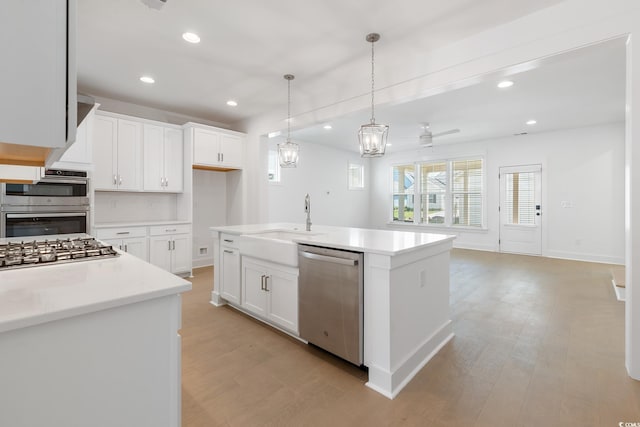 kitchen with ceiling fan, an island with sink, sink, white cabinetry, and appliances with stainless steel finishes