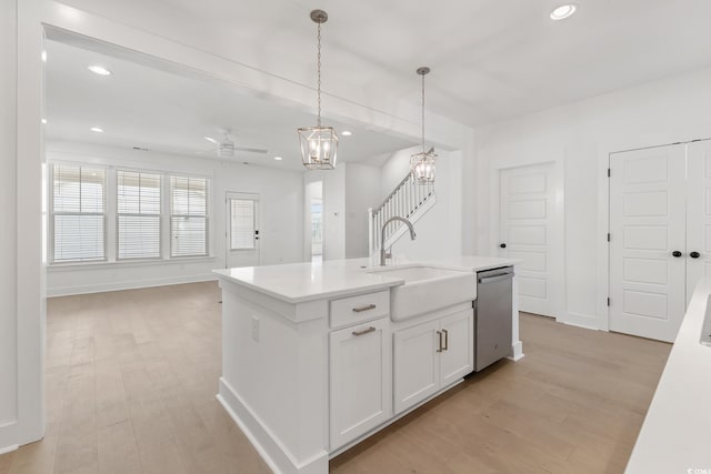 kitchen featuring an island with sink, white cabinets, dishwasher, decorative light fixtures, and sink