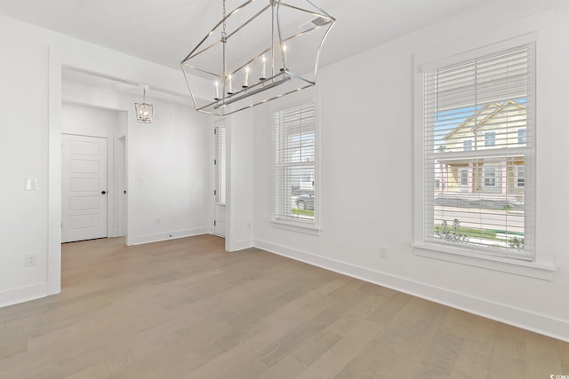 unfurnished dining area with a healthy amount of sunlight, wood-type flooring, and a chandelier