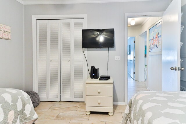 bedroom featuring a closet, light tile patterned floors, and crown molding