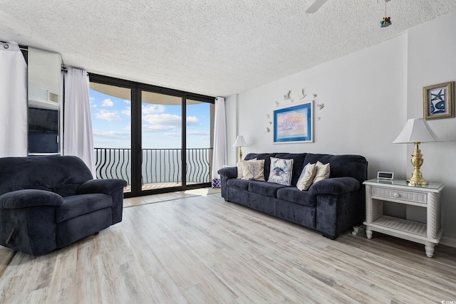 living room featuring floor to ceiling windows, ceiling fan, light hardwood / wood-style flooring, and a textured ceiling