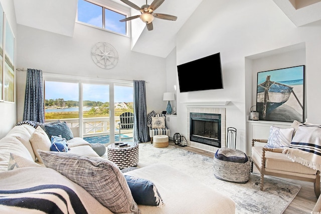 living room with wood-type flooring, a tiled fireplace, ceiling fan, and a wealth of natural light