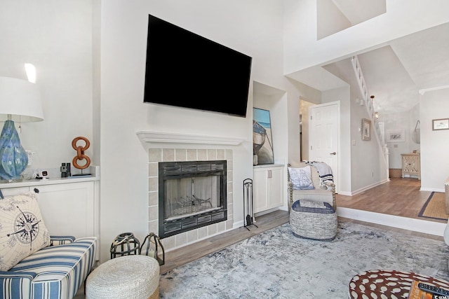 living room featuring high vaulted ceiling, a tiled fireplace, and hardwood / wood-style flooring