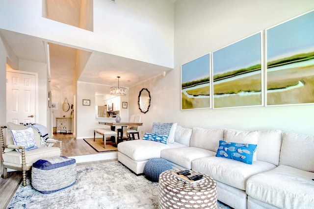 living room featuring an inviting chandelier, wood-type flooring, and a towering ceiling