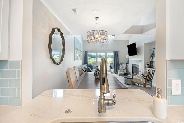 kitchen with sink, decorative light fixtures, a chandelier, crown molding, and hardwood / wood-style floors