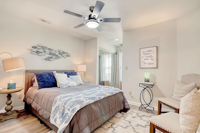 bedroom featuring light wood-type flooring, ceiling fan, and a textured ceiling