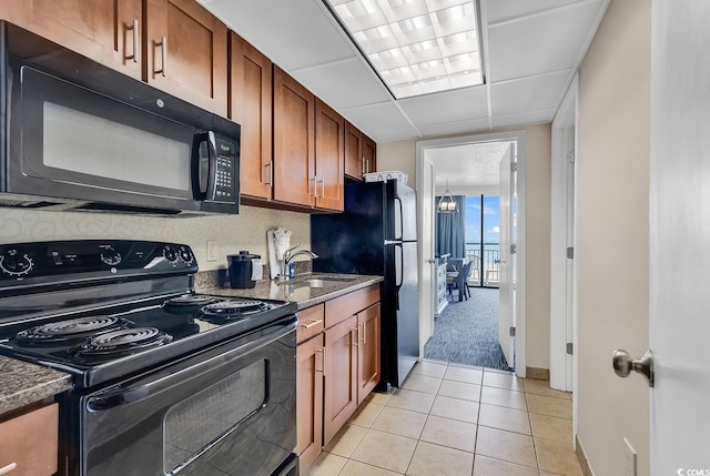 kitchen featuring dark stone counters, black appliances, sink, and light tile patterned floors