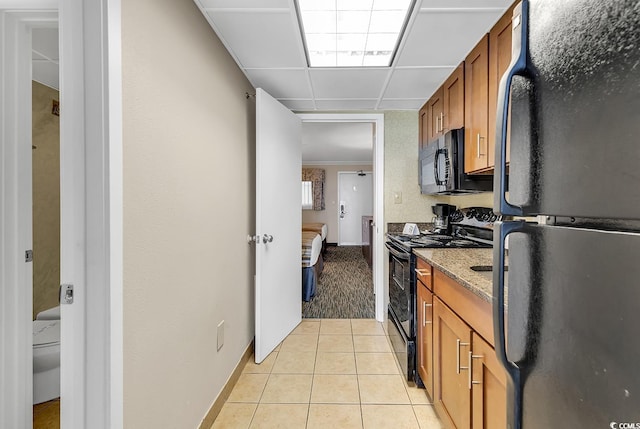 kitchen featuring stone counters, light tile patterned floors, and black appliances