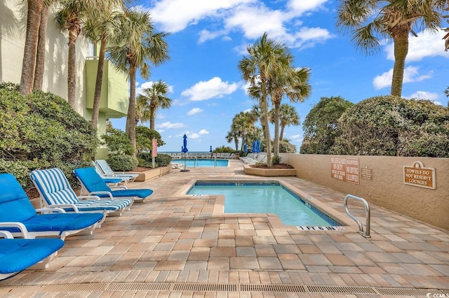 view of pool with a water view and a patio area