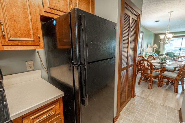 kitchen featuring light hardwood / wood-style floors, black fridge, a textured ceiling, decorative light fixtures, and a chandelier